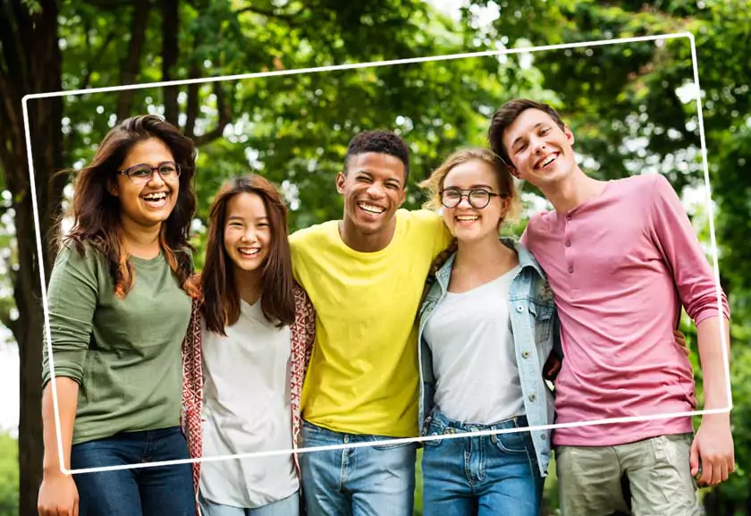 Internationale Jugendbegegnungen und Freiwilligendienste Lachende internationale Jugendgruppe: die jungen Frauen und Männer haben die Arme umeinander gelegt .