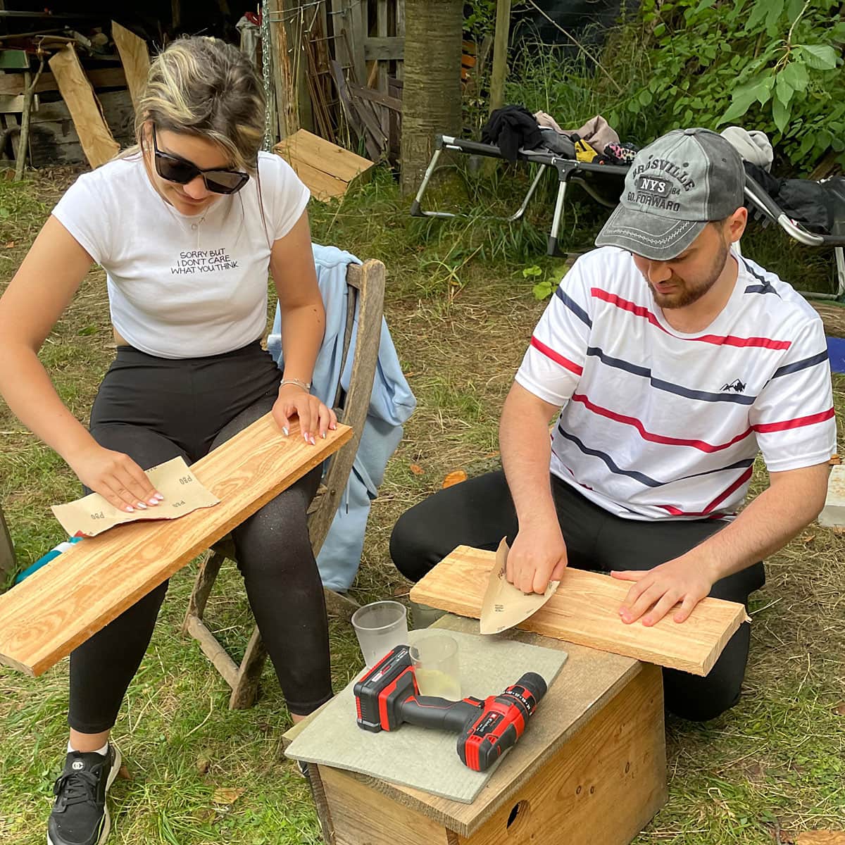 Zwei Teilnehmende schmirgeln Holzbretter ab